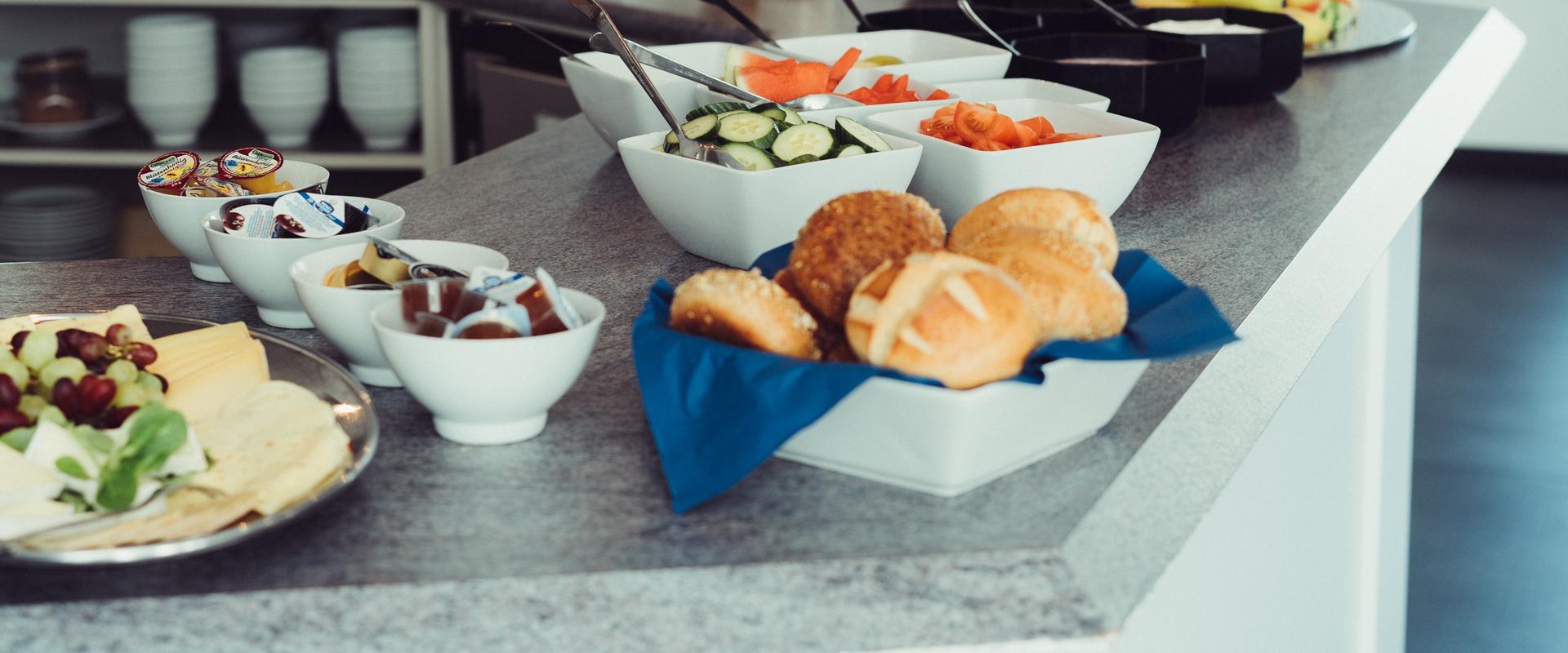 Frühstücksbuffet mit Käseplatte, Brötchen und Obst